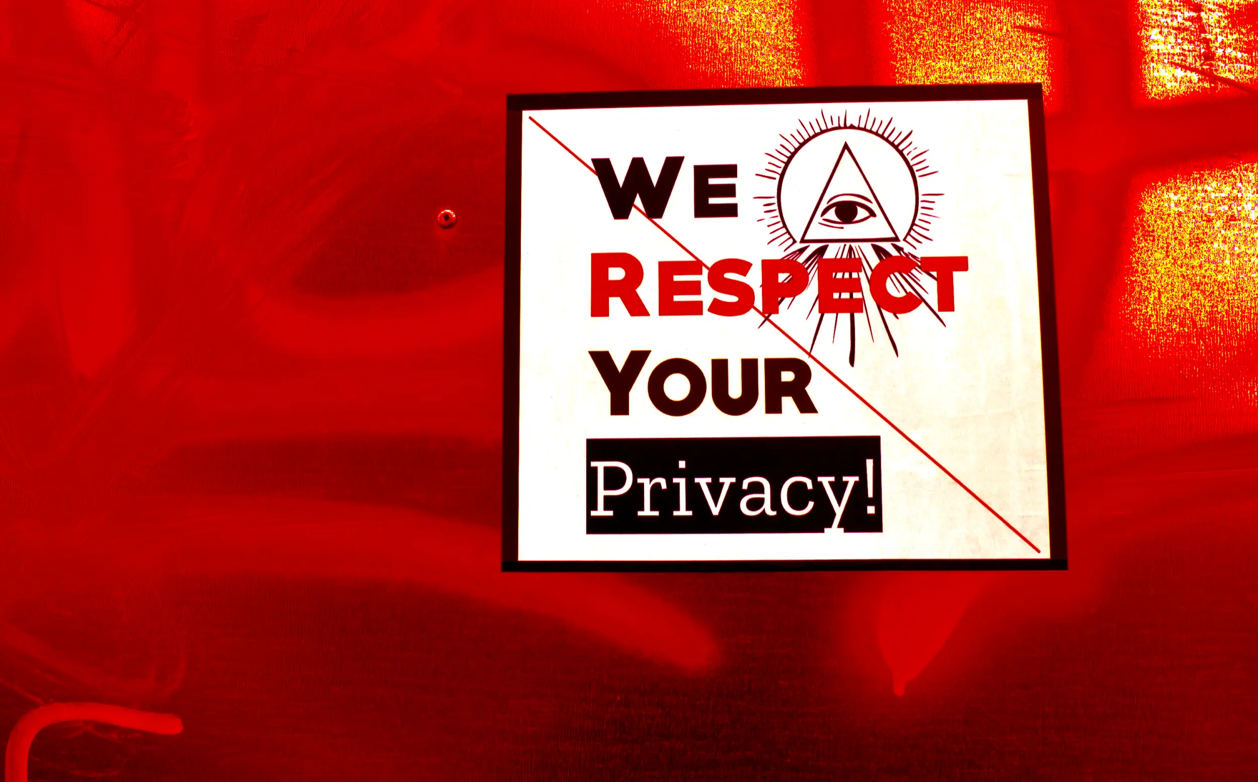 Filtered photo of a sticker on a metallic surface with graffiti. The sticker has the sentence "We respect your privacy!" written on it, and the whole sentence is barred is a red line over it.