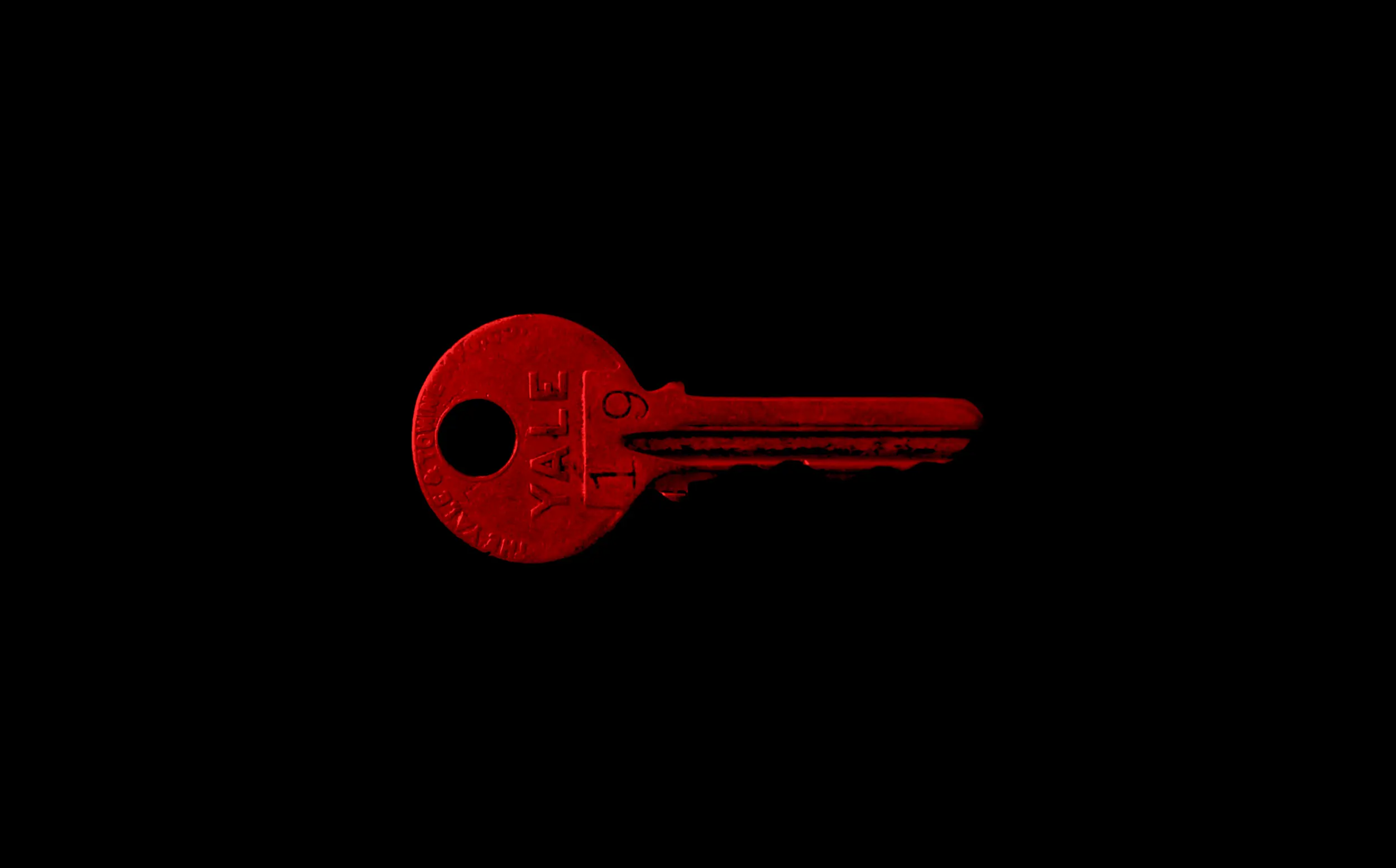 Photo of a red key on an all black background.